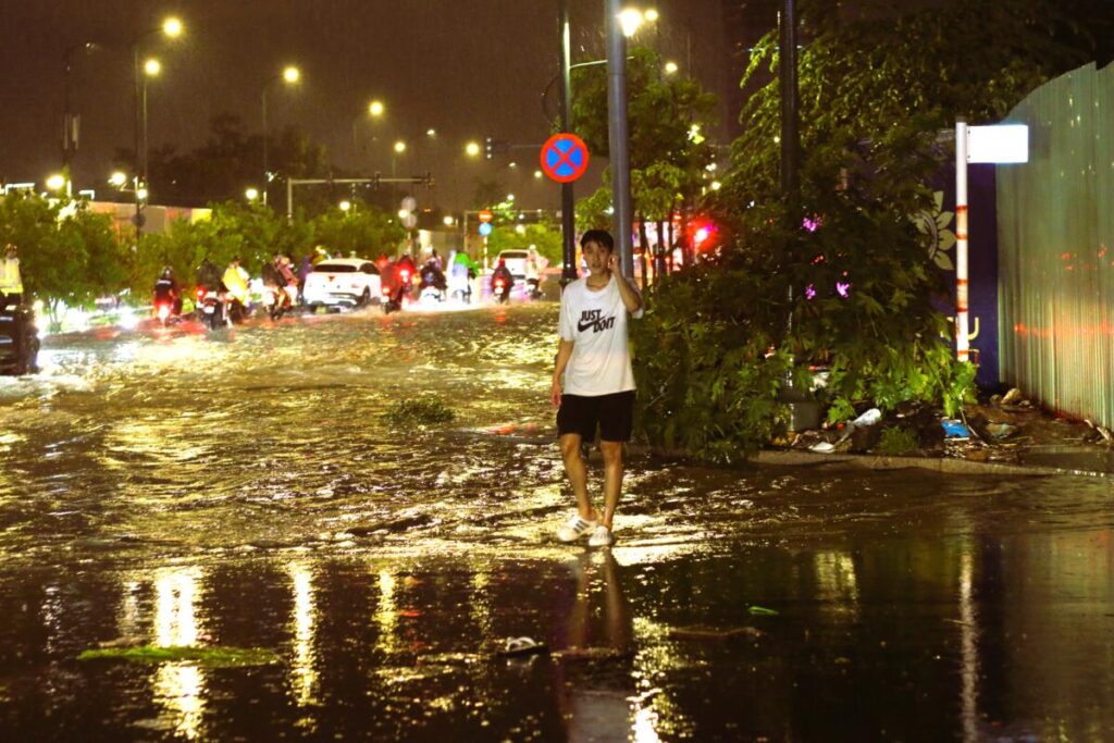 Sài Gòn mưa đêm, thanh niên dừng xe dẫn người đi đường tránh ngập