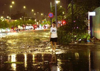 Sài Gòn mưa đêm, thanh niên dừng xe dẫn người đi đường tránh ngập